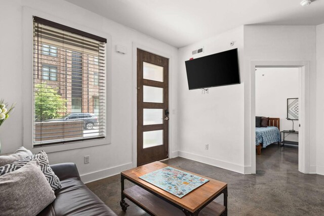 living room with concrete flooring, baseboards, and plenty of natural light