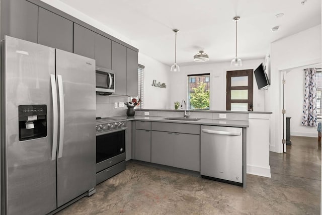 kitchen with appliances with stainless steel finishes, gray cabinetry, a sink, and a peninsula