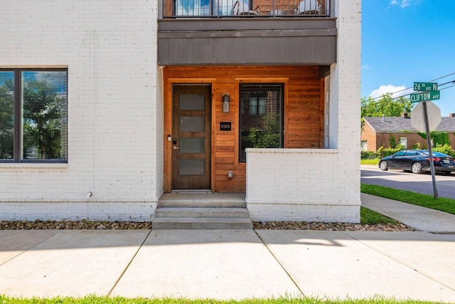 entrance to property with brick siding and a balcony