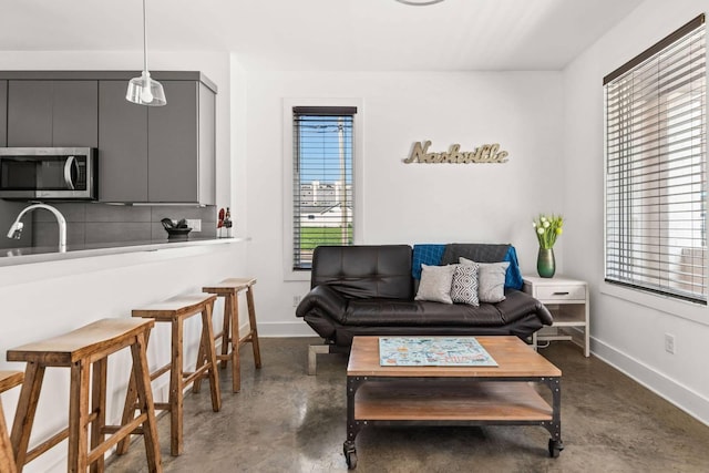 living area featuring finished concrete flooring and baseboards