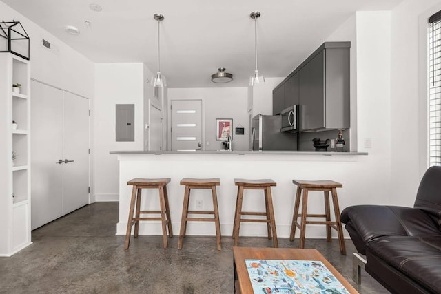 kitchen with electric panel, stainless steel appliances, concrete flooring, and a breakfast bar area