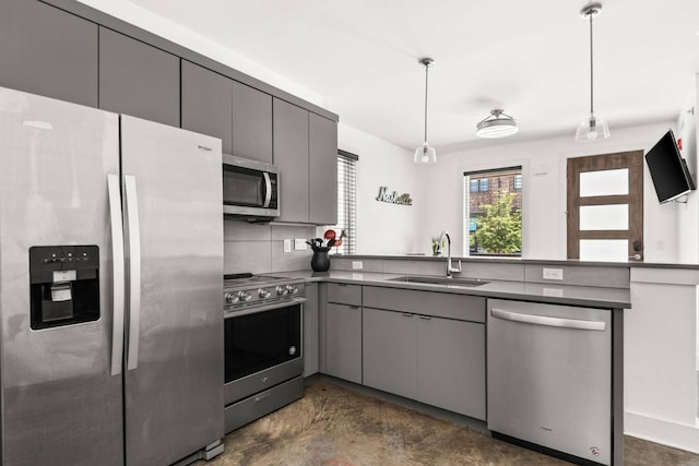 kitchen with appliances with stainless steel finishes, gray cabinetry, a sink, a peninsula, and decorative light fixtures