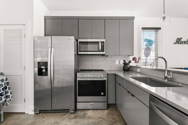 kitchen featuring appliances with stainless steel finishes, gray cabinets, a sink, concrete flooring, and light countertops