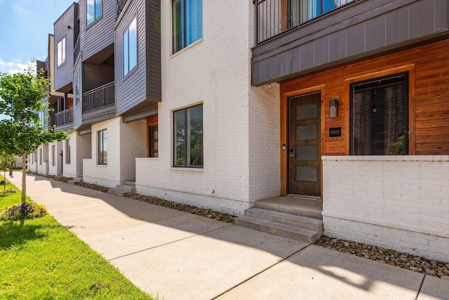 doorway to property with brick siding and a balcony