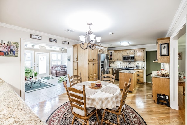 dining space featuring a chandelier, ornamental molding, and light wood-style flooring
