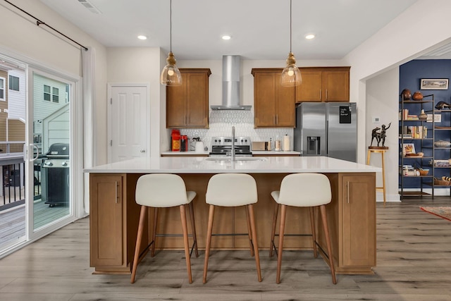 118 Buckfast Ln, Antioch, TN 37013 - kitchen featuring stainless steel appliances, wall chimney exhaust hood, an island with sink, light countertops, and tasteful backsplash