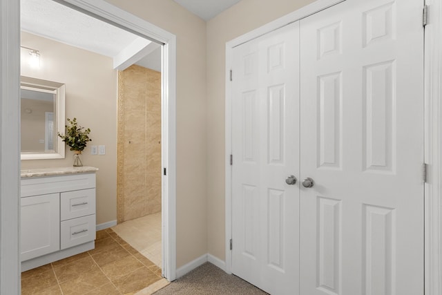 full bathroom featuring vanity, tiled shower, baseboards, and tile patterned floors