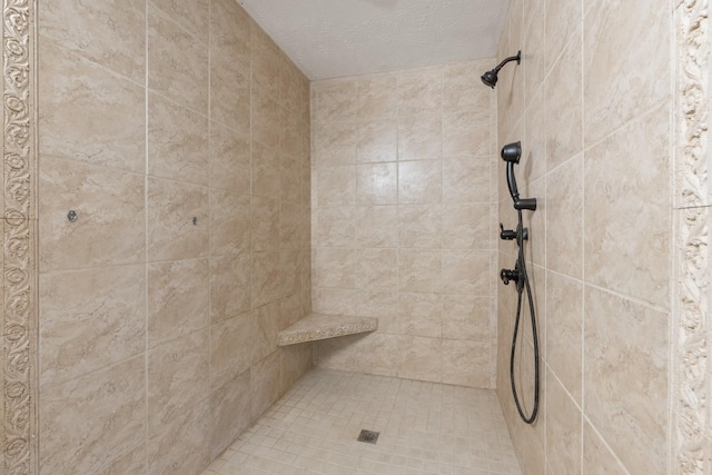 full bath featuring tiled shower and a textured ceiling