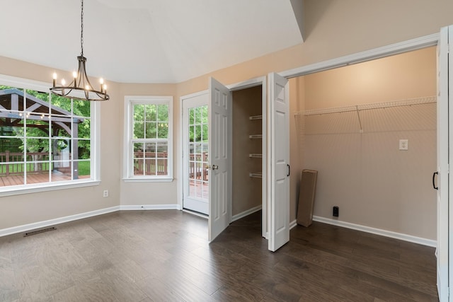 unfurnished dining area with a chandelier, dark wood finished floors, and baseboards