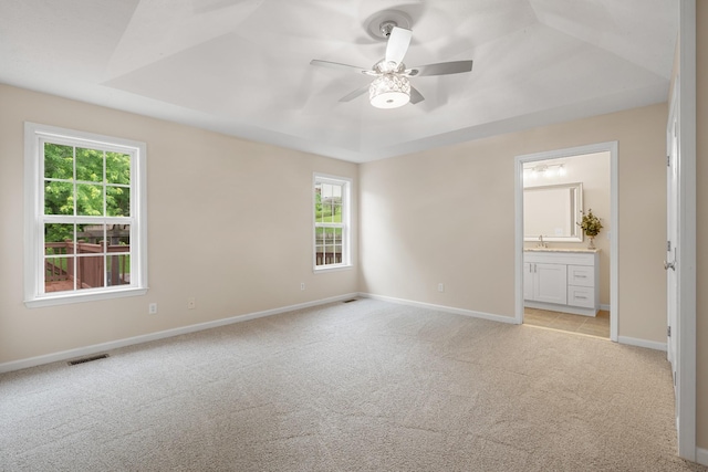 unfurnished bedroom featuring light carpet, multiple windows, baseboards, and a sink