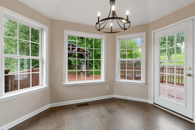 unfurnished dining area featuring a chandelier, baseboards, and dark wood-style floors