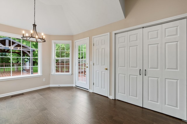 unfurnished dining area featuring a chandelier, dark wood-style floors, and baseboards