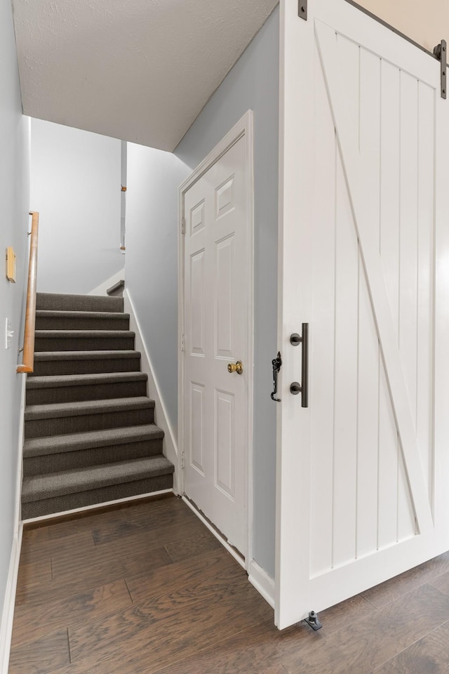 stairs featuring wood finished floors, baseboards, and a barn door