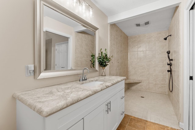 full bathroom featuring a tile shower and vanity