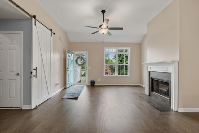 foyer with ceiling fan, a barn door, dark wood-style flooring, a fireplace with flush hearth, and baseboards