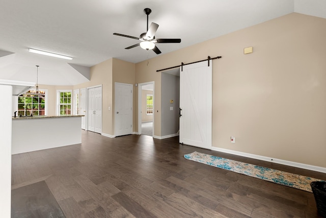 unfurnished living room featuring a barn door, ceiling fan, dark wood finished floors, baseboards, and lofted ceiling