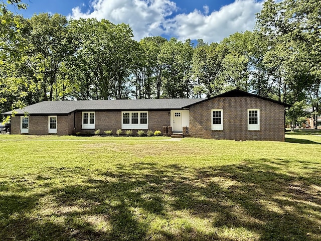ranch-style home with brick siding, a front yard, and view of wooded area