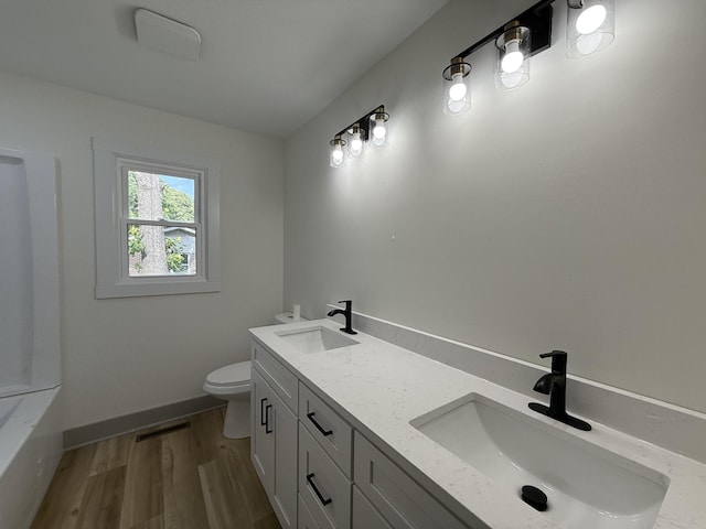 305 Twelve Oaks Rd, Tullahoma, TN 37388 - bathroom with wood finished floors, toilet, double vanity, a tub to relax in, and baseboards