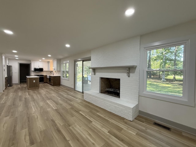 305 Twelve Oaks Rd, Tullahoma, TN 37388 - unfurnished living room featuring a fireplace, light wood-style floors, baseboards, recessed lighting, and a sink