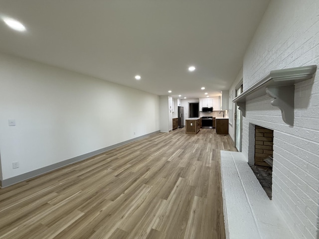 305 Twelve Oaks Rd, Tullahoma, TN 37388 - unfurnished living room with light wood-style flooring, recessed lighting, a brick fireplace, baseboards, and a sink