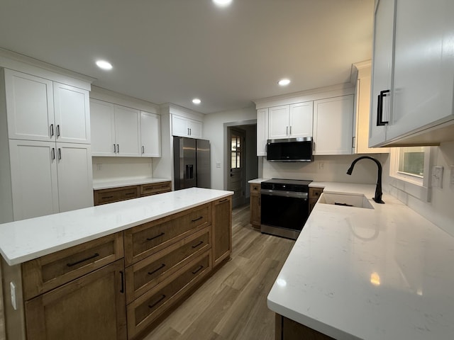 305 Twelve Oaks Rd, Tullahoma, TN 37388 - kitchen featuring appliances with stainless steel finishes, a sink, wood finished floors, white cabinetry, and light stone countertops