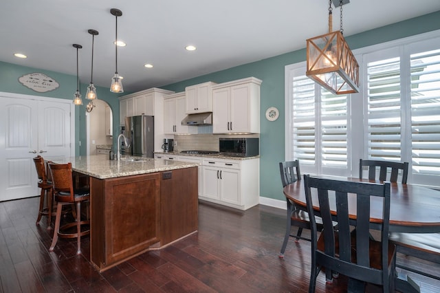 kitchen with stainless steel appliances, backsplash, a sink, recessed lighting, and dark wood-type flooring