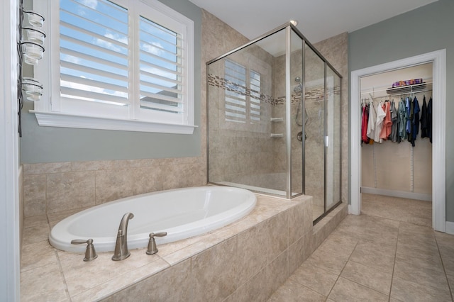 bathroom with a stall shower, a bath, a spacious closet, and tile patterned flooring
