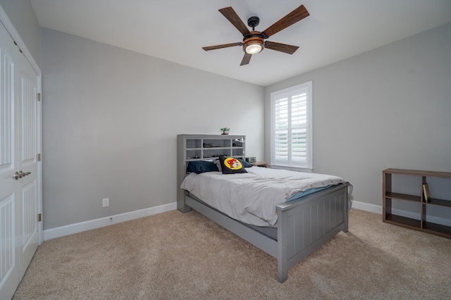bedroom featuring light carpet, baseboards, and a ceiling fan