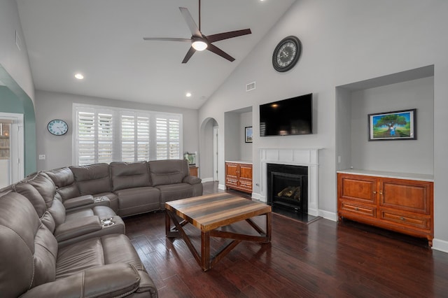 living area featuring a ceiling fan, arched walkways, high vaulted ceiling, dark wood-style floors, and a fireplace