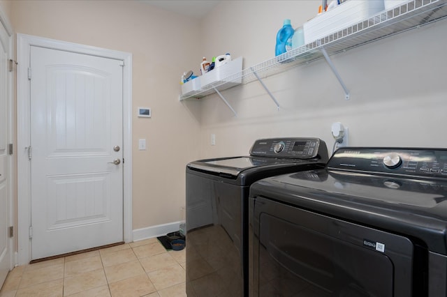laundry area with washing machine and dryer, light tile patterned floors, and baseboards