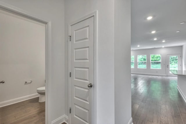 hall featuring baseboards, wood-type flooring, and recessed lighting