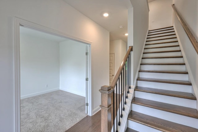 stairway featuring wood finished floors, baseboards, recessed lighting, and carpet