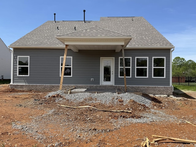 rear view of house featuring fence and roof with shingles