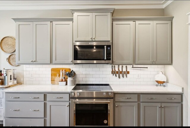 kitchen with stainless steel appliances, gray cabinets, and backsplash