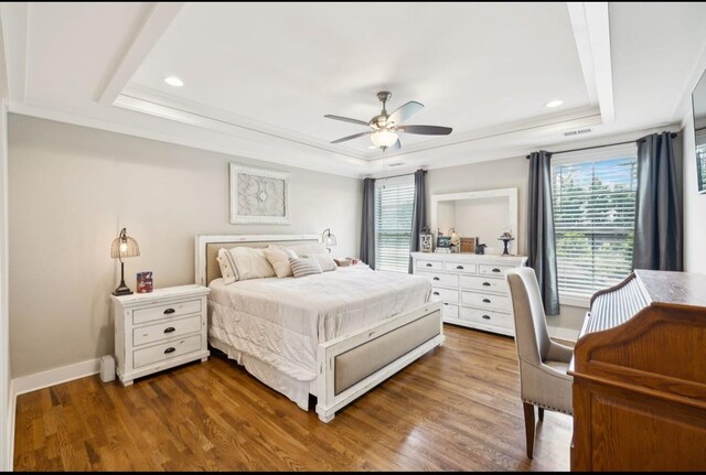 bedroom with a raised ceiling, recessed lighting, wood finished floors, baseboards, and ornamental molding