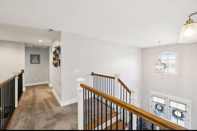 hallway with an upstairs landing, carpet, a chandelier, and baseboards