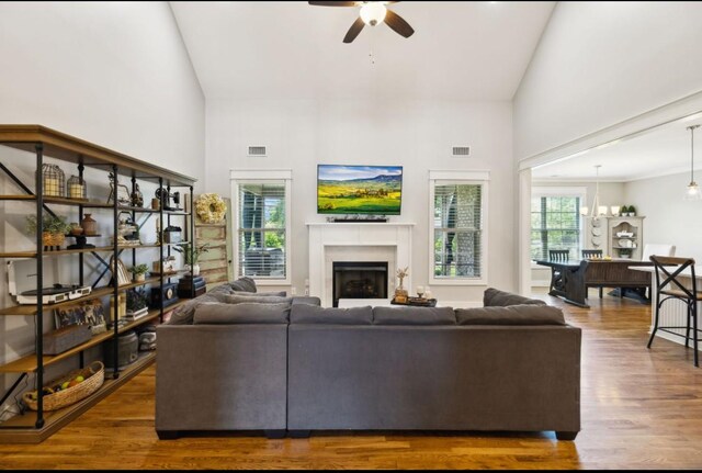 living room with high vaulted ceiling, a ceiling fan, wood finished floors, and a fireplace