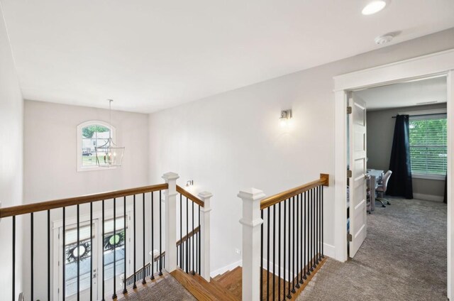 hall featuring an upstairs landing, a chandelier, healthy amount of natural light, and baseboards
