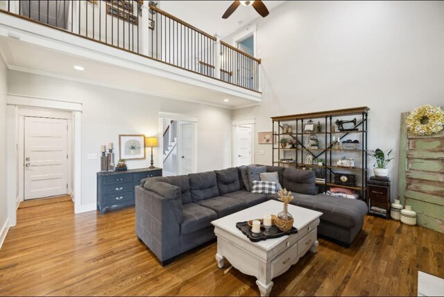living room featuring a high ceiling, ceiling fan, wood finished floors, recessed lighting, and crown molding