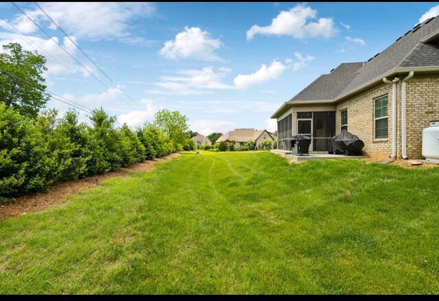 view of grassy yard featuring a sunroom