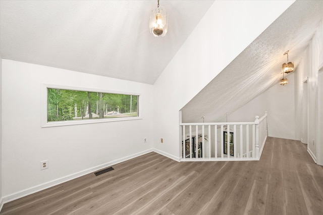 additional living space with wood finished floors, lofted ceiling, and baseboards
