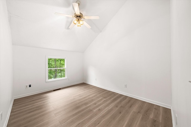 unfurnished room with wood finished floors, vaulted ceiling, baseboards, and a ceiling fan