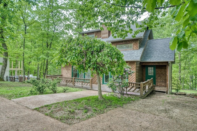 view of front of home featuring covered porch, a chimney, and a shingled roof