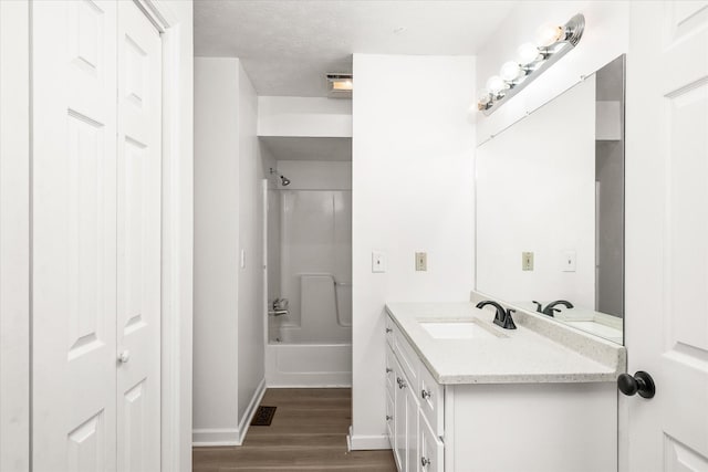 bathroom with wood finished floors, vanity, baseboards, shower / tub combination, and a closet