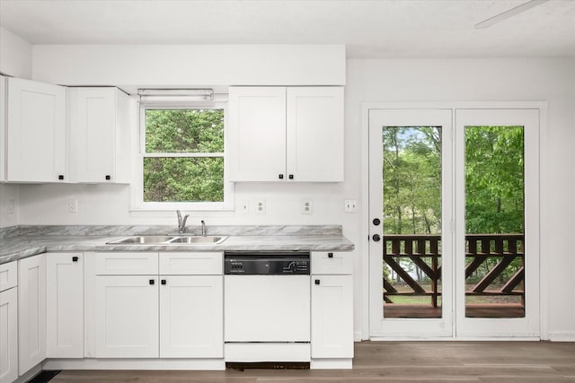 kitchen with white dishwasher, a sink, wood finished floors, and white cabinetry