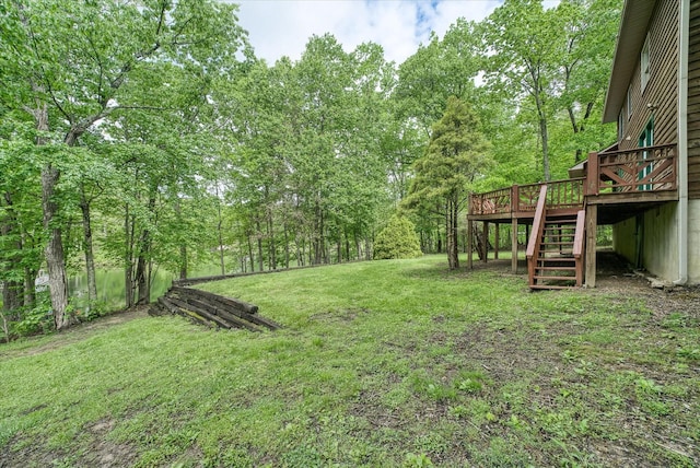 view of green lawn featuring stairway, a deck, and a wooded view