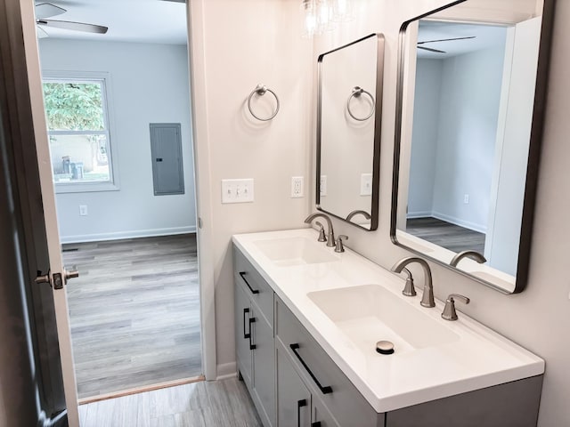 bathroom featuring electric panel, ceiling fan, double vanity, and wood finished floors