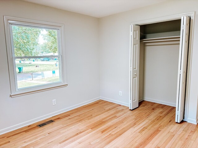 unfurnished bedroom with light wood-style floors, baseboards, and a closet
