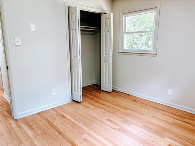 unfurnished bedroom with baseboards, wood finished floors, and a closet
