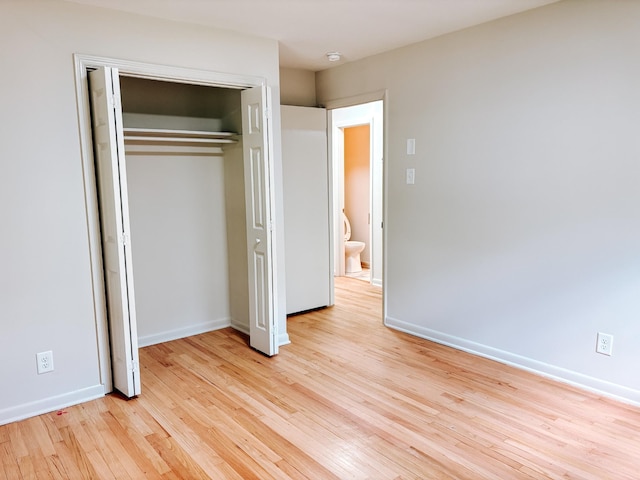 unfurnished bedroom with light wood-style flooring, baseboards, and a closet